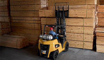 Worker lifting large stack of wood with Cat IC lift truck